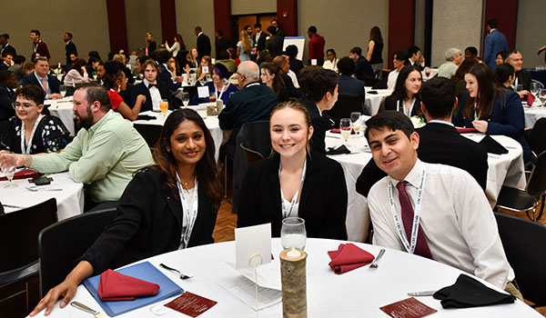Three people posing for a photo at a round table